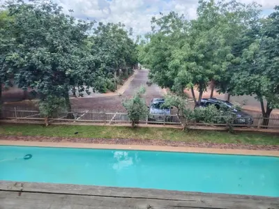 a view of a swimming pool with trees and cars at The Lofts in Hoedspruit