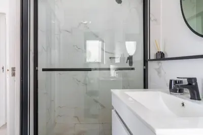 a bathroom with a glass shower and a sink at AlimamaSpaces Mikes Munyaka in Midrand