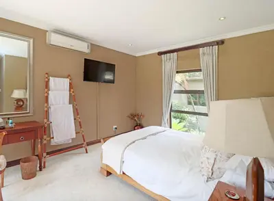 a bedroom with a bed and a tv on the wall at Ubuntu A home away from home in Midrand