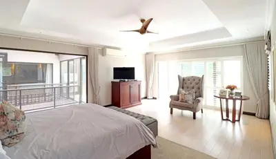 a bedroom with a bed and a chair and a ceiling fan at Ubuntu A home away from home in Midrand