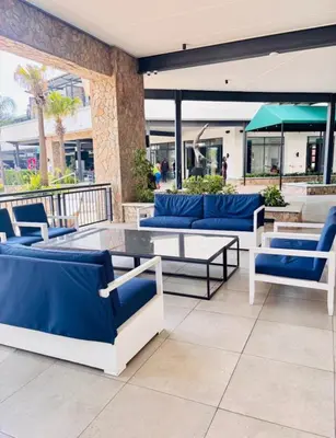 a patio with blue and white chairs and tables at 1 Bedroom Apartment at The Blyde, Pretoria in Pretoria
