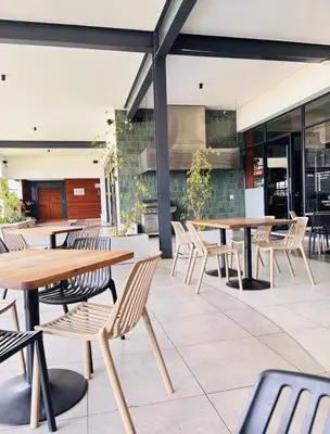 an outdoor patio with wooden tables and chairs at 1 Bedroom Apartment at The Blyde, Pretoria in Pretoria