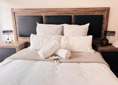 a bed with white pillows and a wooden headboard at 1 Bedroom Apartment at The Blyde, Pretoria in Pretoria