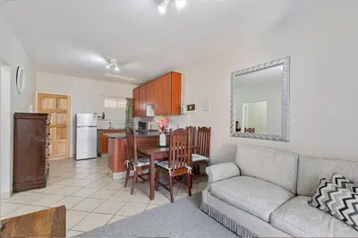 a living room with a couch and a table and a kitchen at Calmwood Stay in Midrand