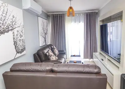 a living room with a leather couch and a television at chillasclub&Bnb in Nelspruit