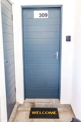 a blue garage door with a welcome mat in front of it at chillasclub&Bnb in Nelspruit