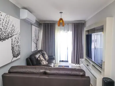 a living room with a leather couch and a television at chillasclub&Bnb in Nelspruit