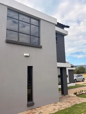 a white house with a window on the side of it at 202 on Crescent - Luxury Wildlife Escape in Hartbeespoort with Magaliesberg Mountain views in Hartbeespoort