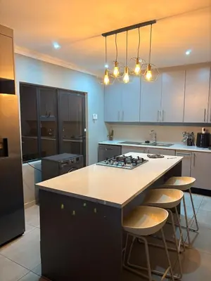 a kitchen with a island with a stove and stools at 202 on Crescent - Luxury Wildlife Escape in Hartbeespoort with Magaliesberg Mountain views in Hartbeespoort