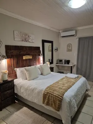 a bedroom with a large bed with a wooden headboard at YouRHome in Pretoria