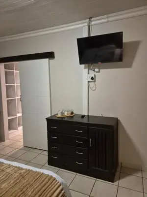 a bedroom with a black dresser with a flat screen tv at YouRHome in Pretoria