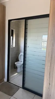 a sliding glass door in a bathroom with a toilet at Lagoon Serenity Suite in Pretoria