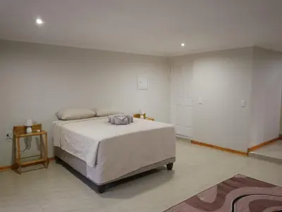 a white bedroom with a bed and a table at Waterhole Lodge Unit 2 in Malelane