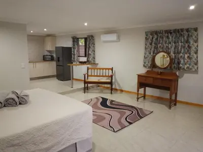 a room with a bed and a table and a kitchen at Waterhole Lodge Unit 2 in Malelane