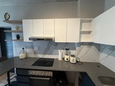 a kitchen with white cabinets and a counter top at The Precinct Luxury Apartments in Kyalami