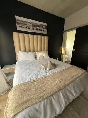 a bedroom with a large bed with white sheets at The Precinct Luxury Apartments in Kyalami