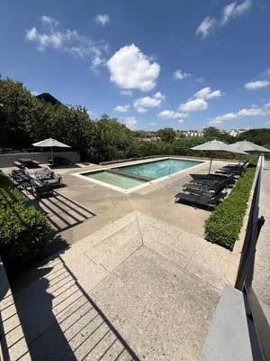 a swimming pool with chairs and umbrellas at The Precinct Luxury Apartments in Kyalami