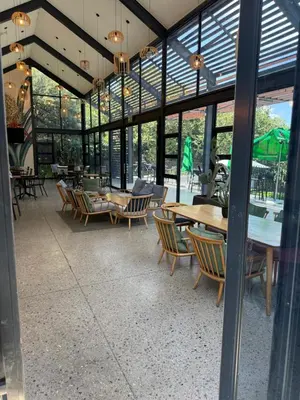 a dining room with tables and chairs and windows at The Precinct Luxury Apartments in Kyalami