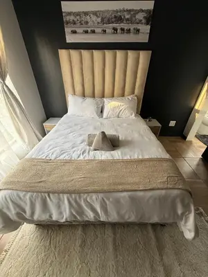 a bedroom with a large bed with white sheets at The Precinct Luxury Apartments in Kyalami