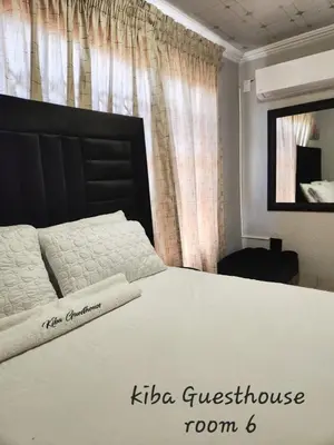 a bedroom with a large white bed with a black headboard at Kiba guest house in Marble Hall