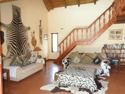a living room with a zebra print couch and stairs at Trees Too Guest Lodge in Komatipoort