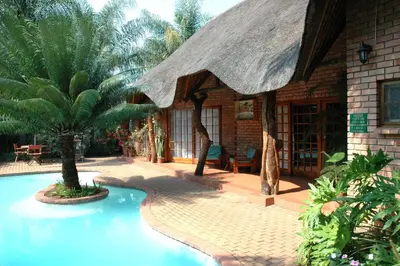 a house with a large swimming pool in front of it at Trees Too Guest Lodge in Komatipoort