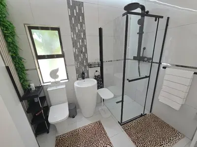 a bathroom with a toilet and a glass shower at Indulge Deluxe Accommodation in Middelburg
