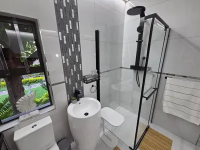 a bathroom with a toilet and a sink and a window at Indulge Deluxe Accommodation in Middelburg