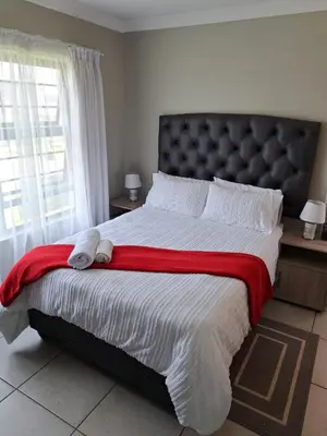 a bedroom with a large bed with a red blanket at GP Mgudlwa in Pretoria