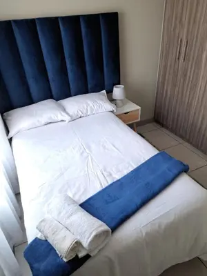 a bed with a blue headboard and towels on it at GP Mgudlwa in Pretoria