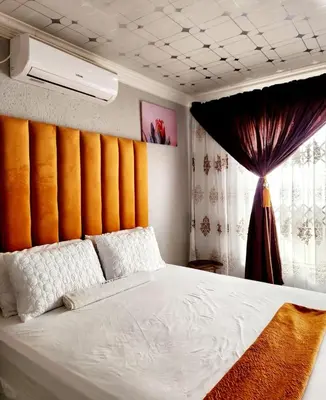 a bedroom with a white bed with an orange wall at Kiba guest house