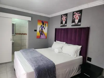 a bedroom with a large bed with a purple headboard at Kiba guest house