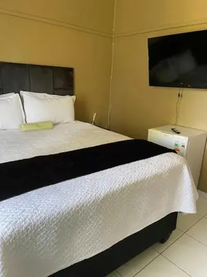 a bedroom with a white bed and a flat screen tv at Guest house at 17 Arnot