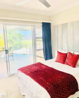 a bedroom with a large bed with red pillows at Damview guesthouse in Hartbeespoort