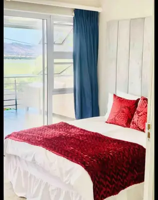 a bedroom with a bed with red pillows and a window at Damview guesthouse in Hartbeespoort