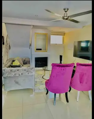 a living room with pink chairs and a couch at Damview guesthouse in Hartbeespoort