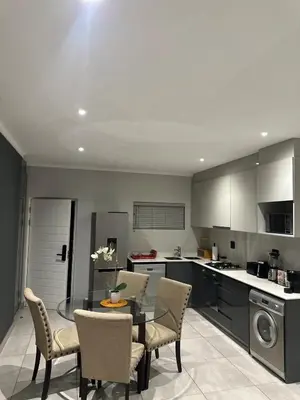 a kitchen with a table and chairs in a kitchen at Modern Comfort in the Heart of Pretoria the Jacaranda City in Pretoria