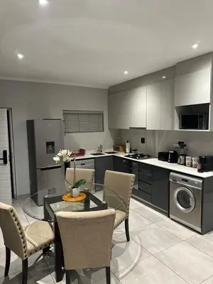 a kitchen with a table and chairs in a kitchen at Modern Comfort in the Heart of Pretoria the Jacaranda City in Pretoria