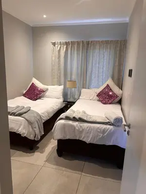 two beds in a room with a window at Modern Comfort in the Heart of Pretoria the Jacaranda City in Pretoria