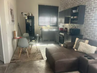a living room with a couch and a table and a kitchen at Kumba Mzansi in Musina