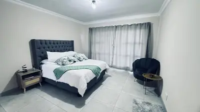 a bedroom with a bed and a chair and a window at Casa Tranquila Luxe in Pretoria