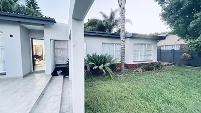 a white house with a palm tree in the yard at Casa Tranquila Luxe in Pretoria
