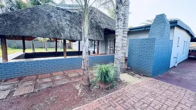 a house with a thatched roof and a palm tree at Casa Tranquila Luxe in Pretoria