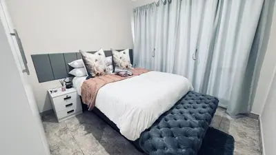 a bedroom with a large bed with a black ottoman at Casa Tranquila Luxe in Pretoria