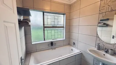 a bathroom with a tub and a sink and a window at Casa Tranquila Luxe in Pretoria