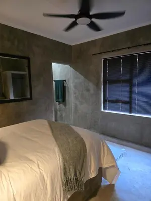 a bedroom with a bed with a ceiling fan at Villa Calao in Marloth Park