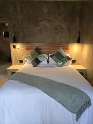 a bedroom with a bed with white sheets and pillows at Villa Calao in Marloth Park