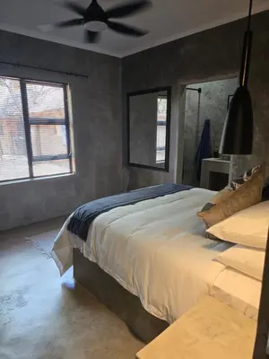 a bedroom with a bed and a ceiling fan at Villa Calao in Marloth Park