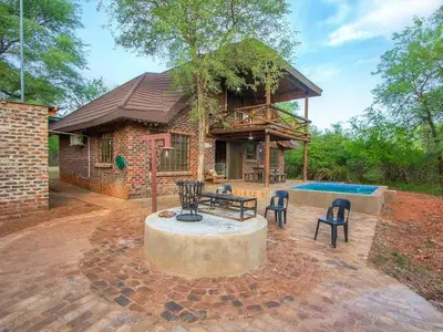 a house with a table and chairs and a pool at Optibos - 3 Bedroom Holiday Home 6 Sleeper in Marloth Park