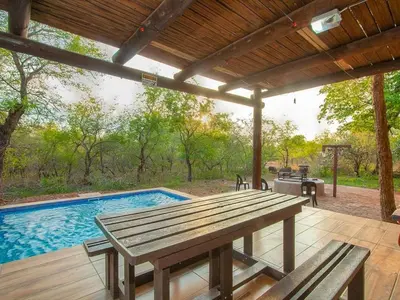 a patio with a picnic table and a swimming pool at Optibos - 3 Bedroom Holiday Home 6 Sleeper in Marloth Park